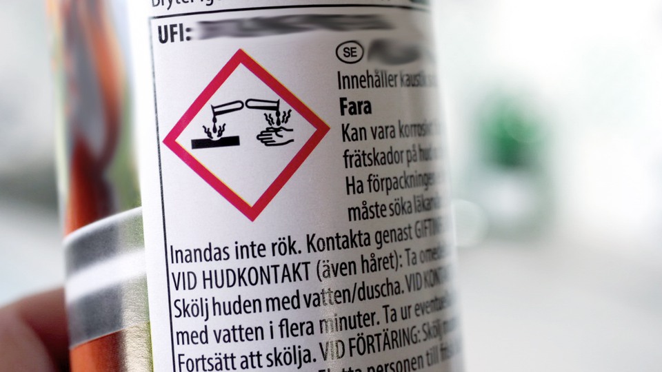 En flaska med en frätande kemiska produkt och märkning med faropiktogram.