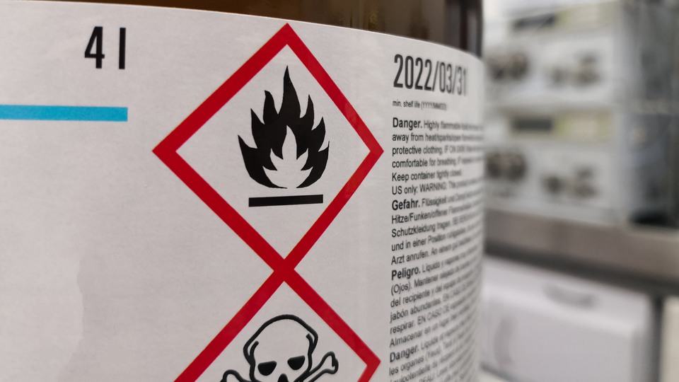 Etikett på en flaska med två olika faromärkningar samt varningstext.